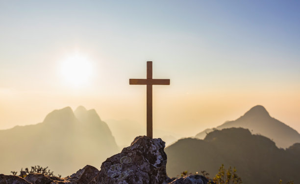 在山顶的十字架符号的剪影与明亮的阳光在彩色的天空背景图片下载