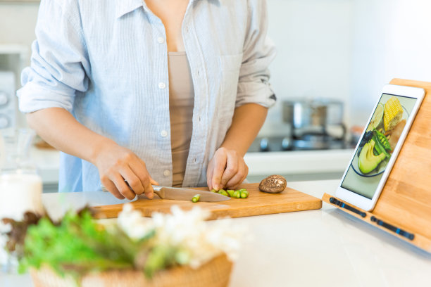 切菜和学习在平板上做饭，家庭主妇在厨房做饭的手特写照片图片下载