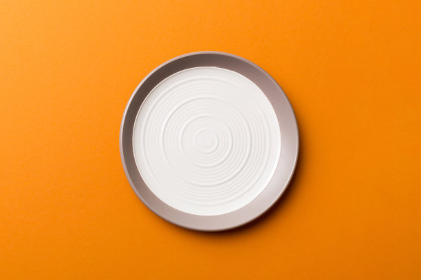 俯视图孤立的彩色背景空圆形白色盘子的食物。空盘子，为你的设计留出空间图片下载
