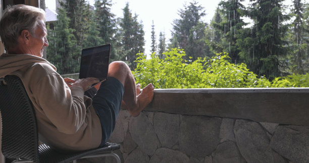 老人在阳台上使用笔记本电脑图片下载