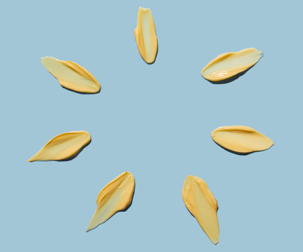 在蓝色背景上以太阳光线的形式涂抹的面霜状的化妆品。防晒膏。副本的空间。图片下载