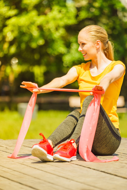 女孩在户外做运动，使用阻力健身带。图片下载