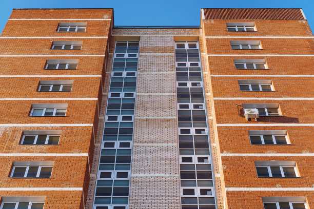 一个由几栋高层建筑组成的新现代住宅区，明亮的外墙与蓝天相映成趣。图片下载