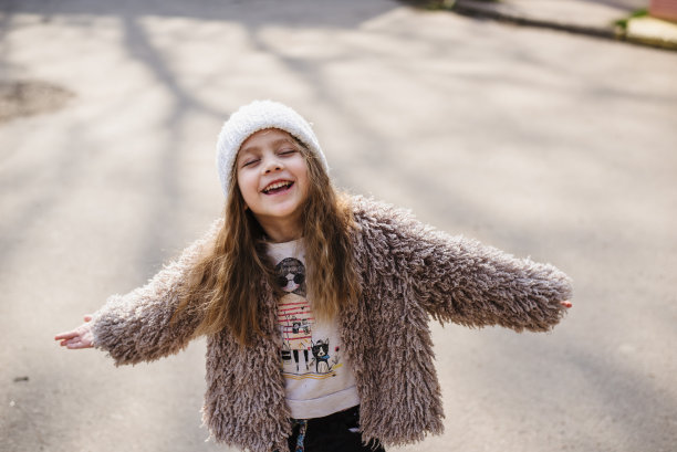 一个美丽的金发女孩的肖像，她闭上眼睛享受春天的阳光。时尚宝宝在一个轻背景。漂亮的四岁孩子喜欢在户外玩耍。维生素D图片下载
