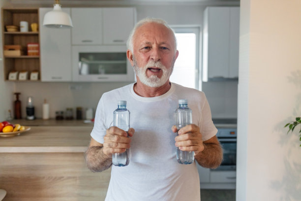 老人拿着水瓶在家锻炼的剪影。图片下载