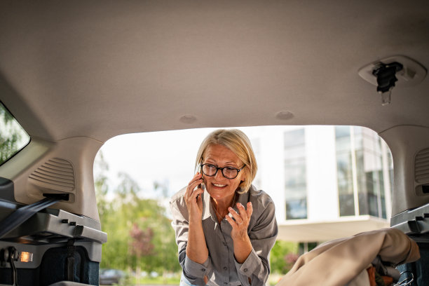 一位成熟的商务女性正在把她的衣柜和商务用品装进车里，因为她要为出差做准备。图片下载