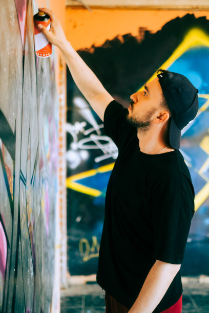 年轻的白人涂鸦艺术家在墙上画画。图片下载
