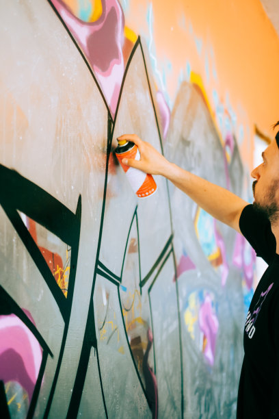 年轻的白人涂鸦艺术家在墙上画画。图片下载