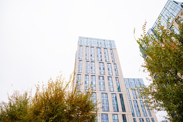 蓝色米色现代公寓大楼，树。瓷砖和玻璃立面。从街上看，从下面看。图片下载