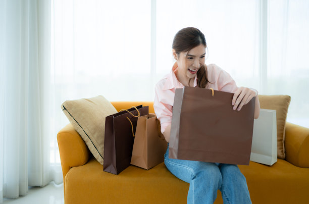 一个美丽的亚洲女人微笑着从购物袋里拿东西。图片下载
