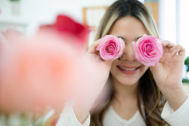 微笑的亚洲妇女在家里手里拿着粉红色的花图片下载