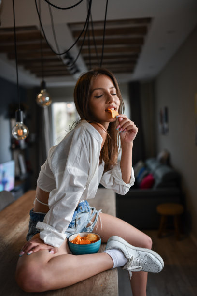 为坐在厨房柜台上的性感女性准备的薯片点心图片下载