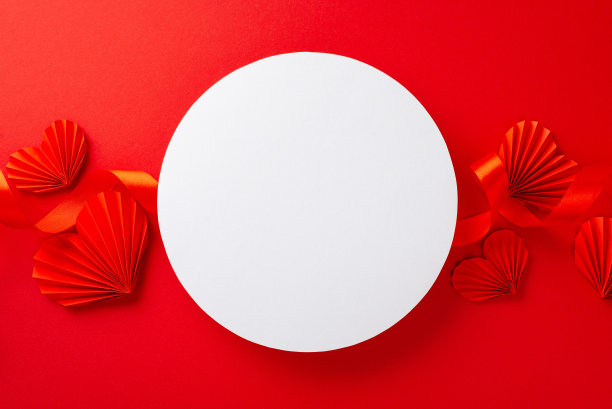白色的空圈的俯视图照片包围着明亮的红色丝带和纸折纸心在孤立的红色背景与复制空间图片下载