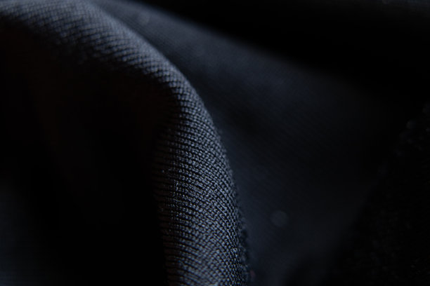 黑色光滑面料搭配波浪作为背景，黑色背景，时尚图片下载