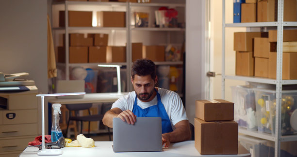 穿着看门人制服的男性黑客在现代仓库窃取笔记本电脑上的信息图片下载