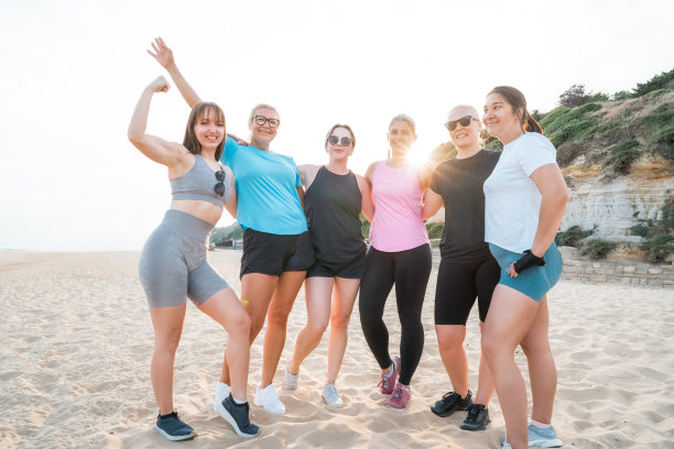 一群不同年龄的活跃女性在锻炼训练后站在沙滩上，对着镜头微笑。运动中的女性同伴在健身后休息。健康和幸福。图片下载