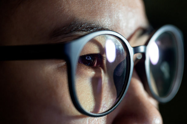 特写镜头的女人眼睛在眼镜反射一个工作的电脑蓝屏图片下载