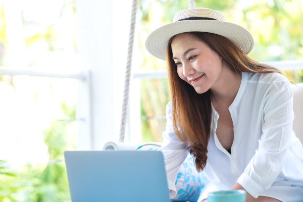 一个美丽的年轻亚洲女人的肖像形象使用笔记本电脑远程工作或学习在线坐在秋千沙发上图片下载