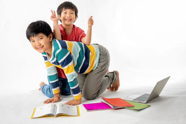 快乐的亚洲男孩的肖像，哥哥在地板上与笔记本电脑和书籍隔离在白色背景，教育和学习与技术概念图片下载