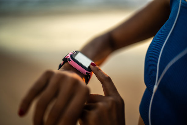 运动女性在沙滩上跑步和查看智能手表上的统计数据的特写图片下载