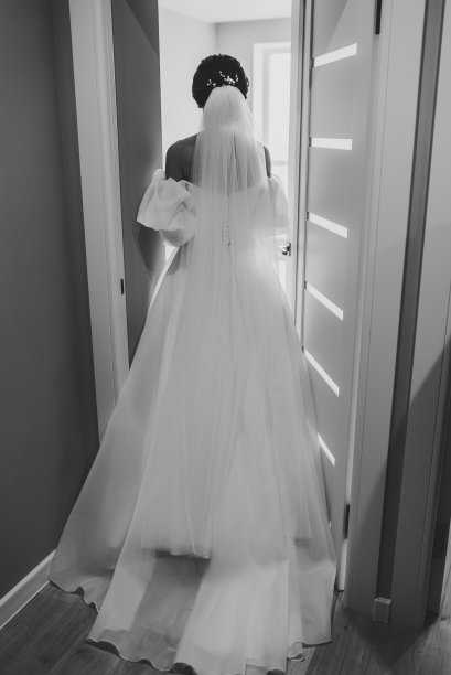 新娘回到新郎身边，惊喜。女人打开房间的门。后视图。新婚快乐。第一次见面是新婚夫妇在家里。黑白照片。特写镜头图片下载
