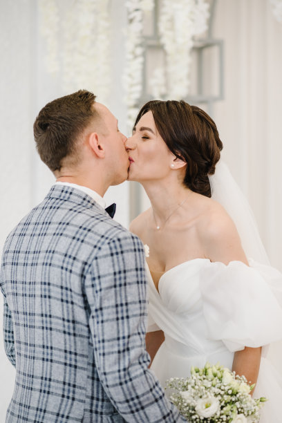 婚姻。参与。新婚夫妇站在装饰着白花的拱门下举行婚礼。新娘和新郎结婚并戴上结婚戒指。女人和男人同时举行仪式。婚纱照片。誓言图片下载