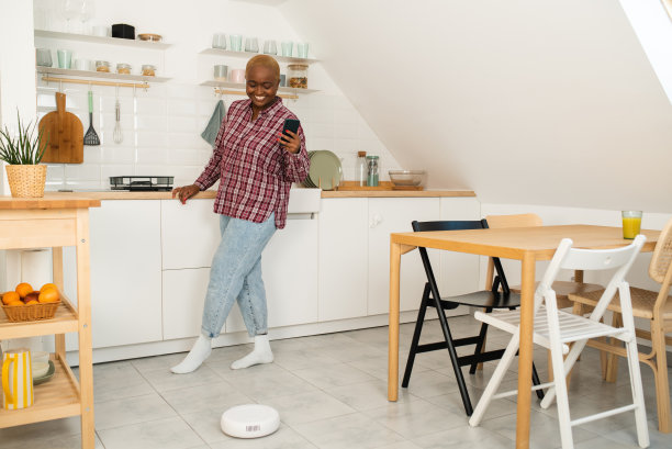 年轻女子用智能应用打开她的机器人吸尘器图片下载