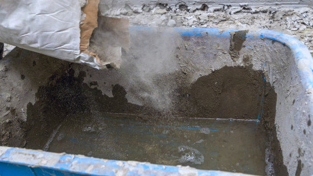 建筑工人把水泥倒进桶里。混合的粘合剂。等待与水泥混合。图片下载