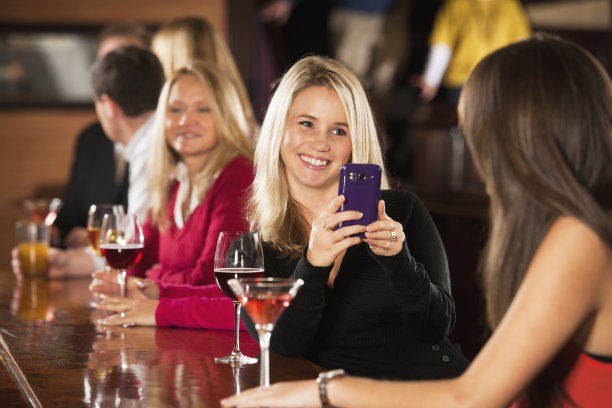 一名女子在酒吧用手机拍照图片下载