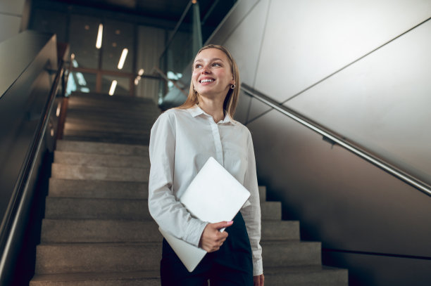 苗条优雅的女人站在办公中心的楼梯上图片下载
