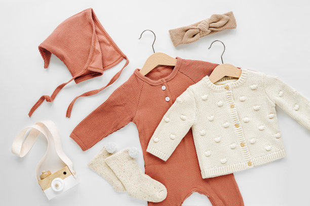 白色床上成套婴儿连衣裤、帽子、发带及针织套头衫。时尚婴儿服装和配件。平铺，俯视图图片下载