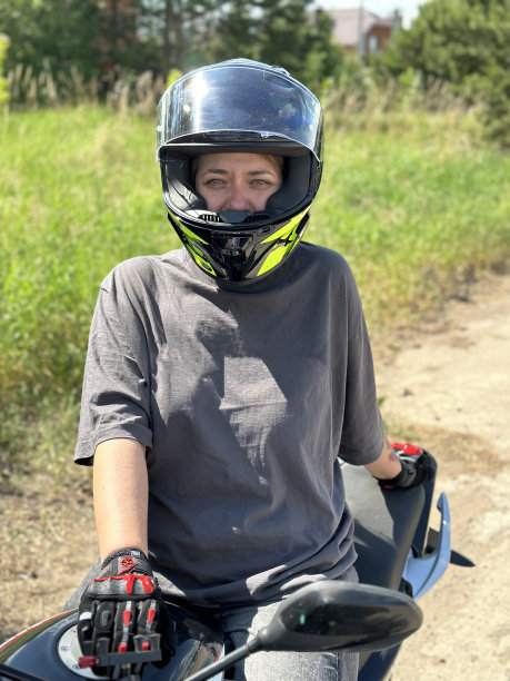 戴着头盔和手套骑摩托车的年轻女子图片下载