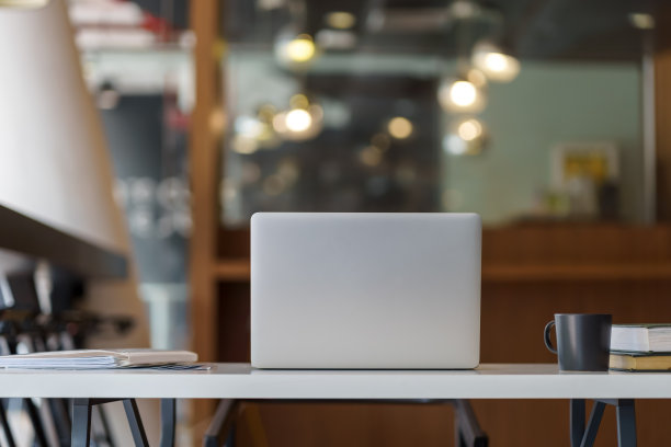 背景模糊的现代商务办公室桌上笔记本电脑的背面视图。图片下载