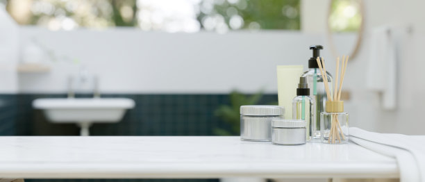 一套现代洗漱用品，一条毛巾，在一个现代浴室的白色桌面上的复印空间。图片下载