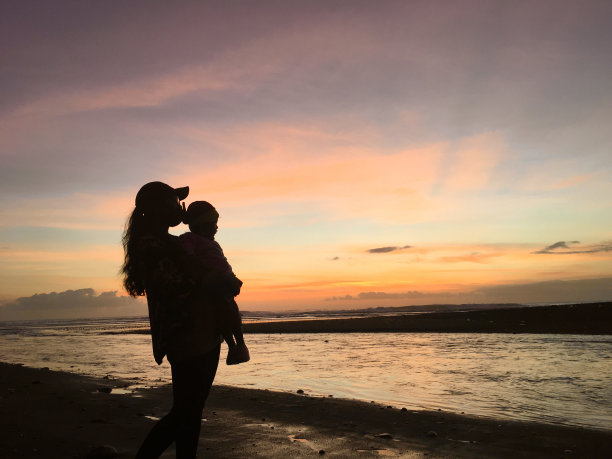 母亲和孩子在沙滩上的剪影照片与日落的背景图片下载