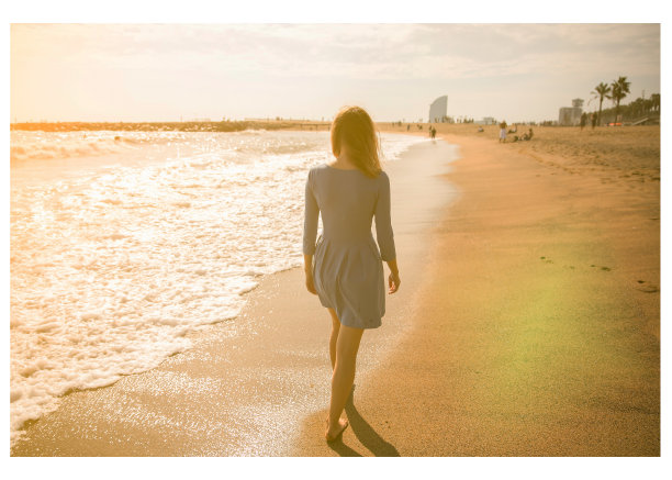 穿着蓝色衣服的漂亮女孩正在海滩上散步。惊人的夏日照片。海边的女人。快乐和有趣的情绪。假日旅游概念。苗条的腿。温暖的海水。图片下载