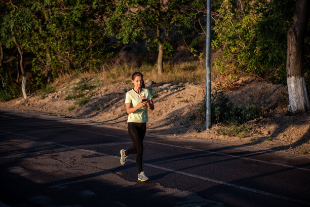 穿着运动服的苗条女孩正在慢跑，手里拿着智能手机。女商人在打电话图片下载