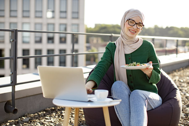 女士端着盘子，在外面用笔记本电脑打字图片下载