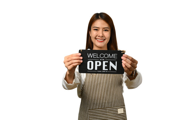 企业主穿着围裙，举着开放的标志，对着镜头微笑图片下载