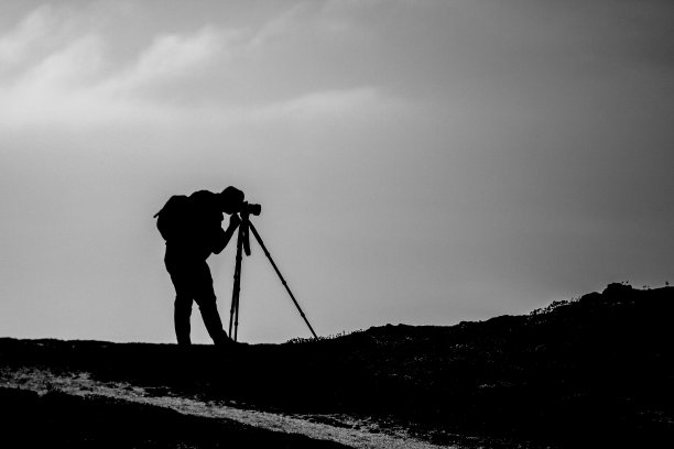 一个带着三脚架和背包的摄影师在户外拍摄风景或肖像的剪影图片下载