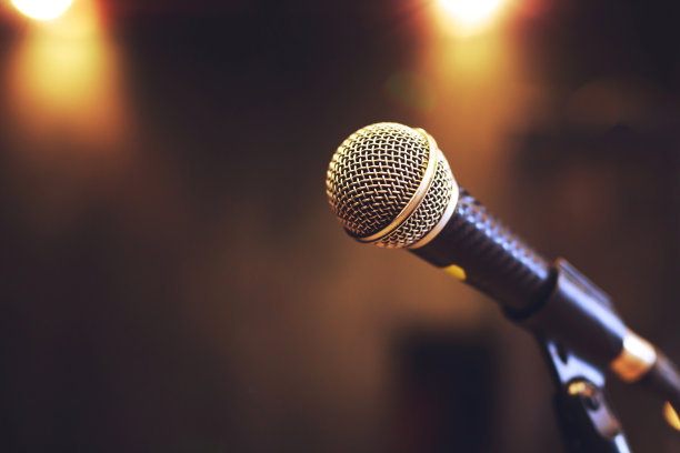 音乐厅或会议室舞台灯光上的麦克风特写。复制空间横幅。软的焦点。图片下载