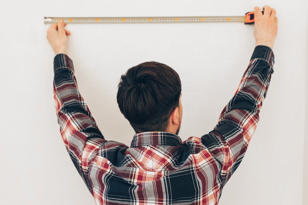 建筑工人用卷尺量墙图片下载