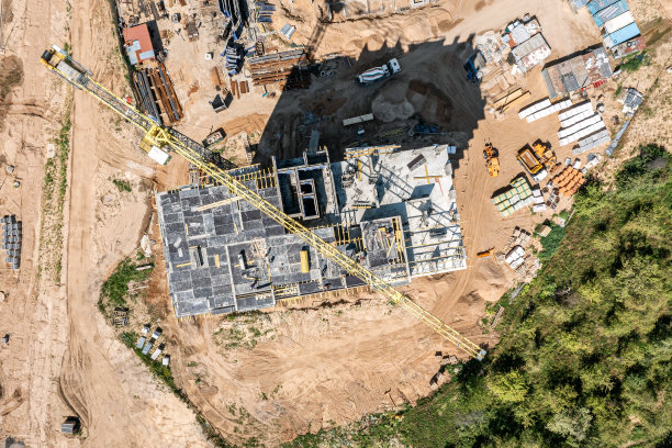 建筑工地鸟瞰图。正在施工的公寓楼附近工作的黄色起重机。图片下载