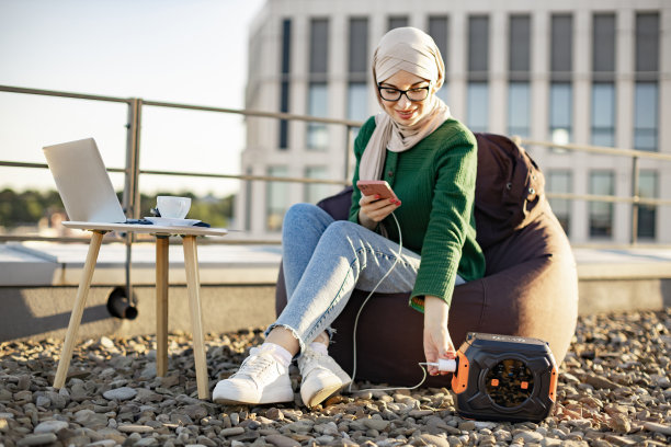 穆斯林妇女将手机连接到露台上的充电站图片下载