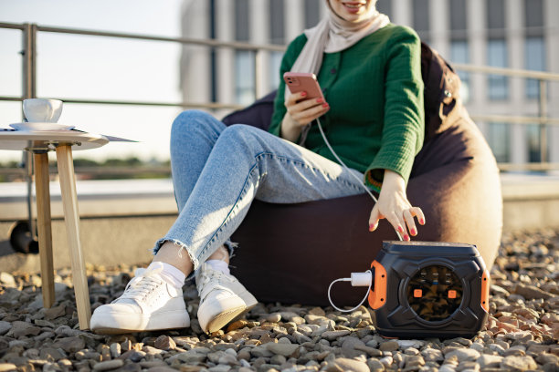 妇女使用手机，因为户外有便携式充电站图片下载