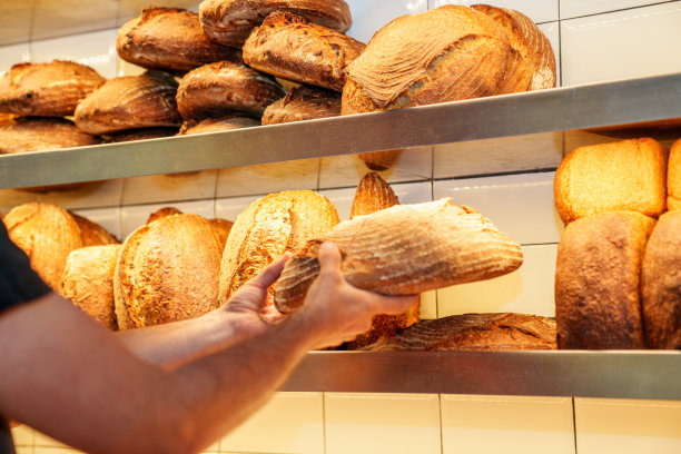 面目全非的面包房工人把刚烤好的面包放在展示架上图片下载