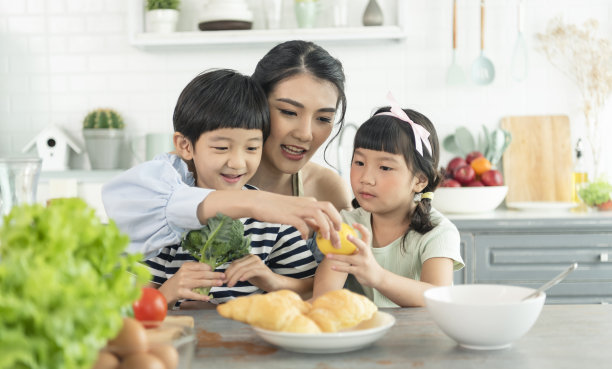 亚洲年轻单身母亲与儿子和女儿在厨房。一起享受家庭活动。图片下载