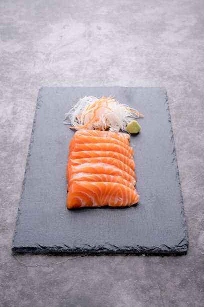 三文鱼生鱼片被放在一个黑石盘上图片下载