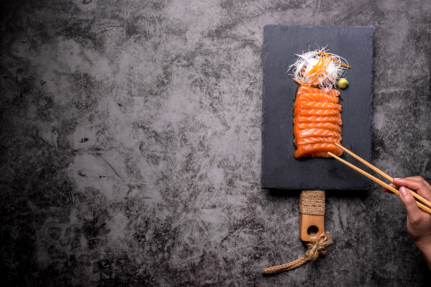 三文鱼生鱼片被放在一个黑石盘上图片下载