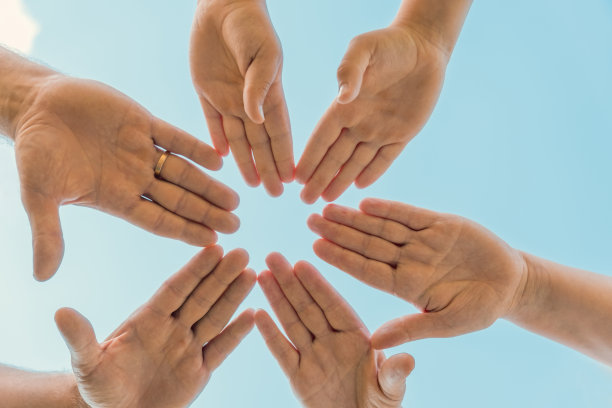 携手成为一个团队。业务团队合作。近距离的一群朋友聚会携手在一起。多样性的人。合作志愿者社区。多元的多民族合作伙伴。蓝天背景图片下载